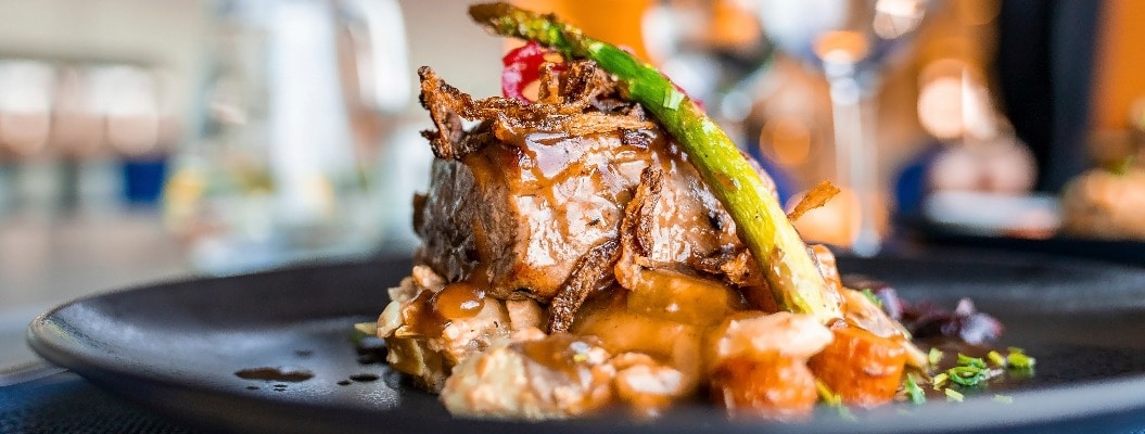 Close-Up of healthy gourmet meal served in black plate. Tasty food displayed on dining table at restaurant. Delicious dinner at luxurious resort.