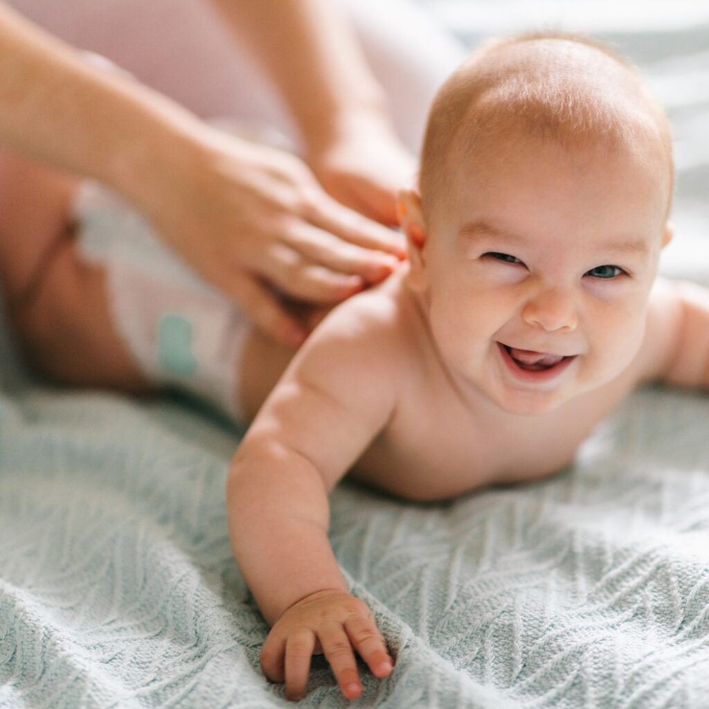 Massage for the baby. Four month old baby smiling doing gymnastics