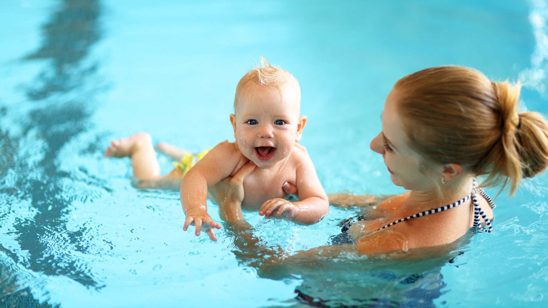 mother teaching baby swimming pool