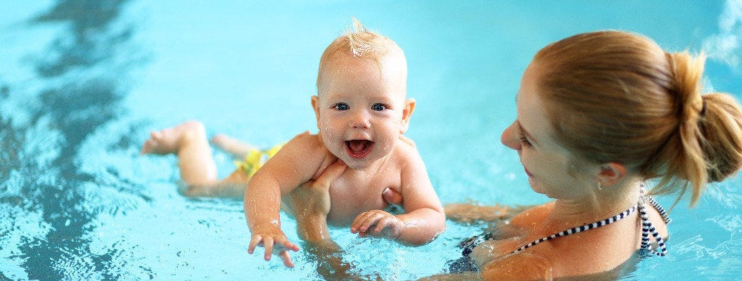 mother teaching baby swimming pool