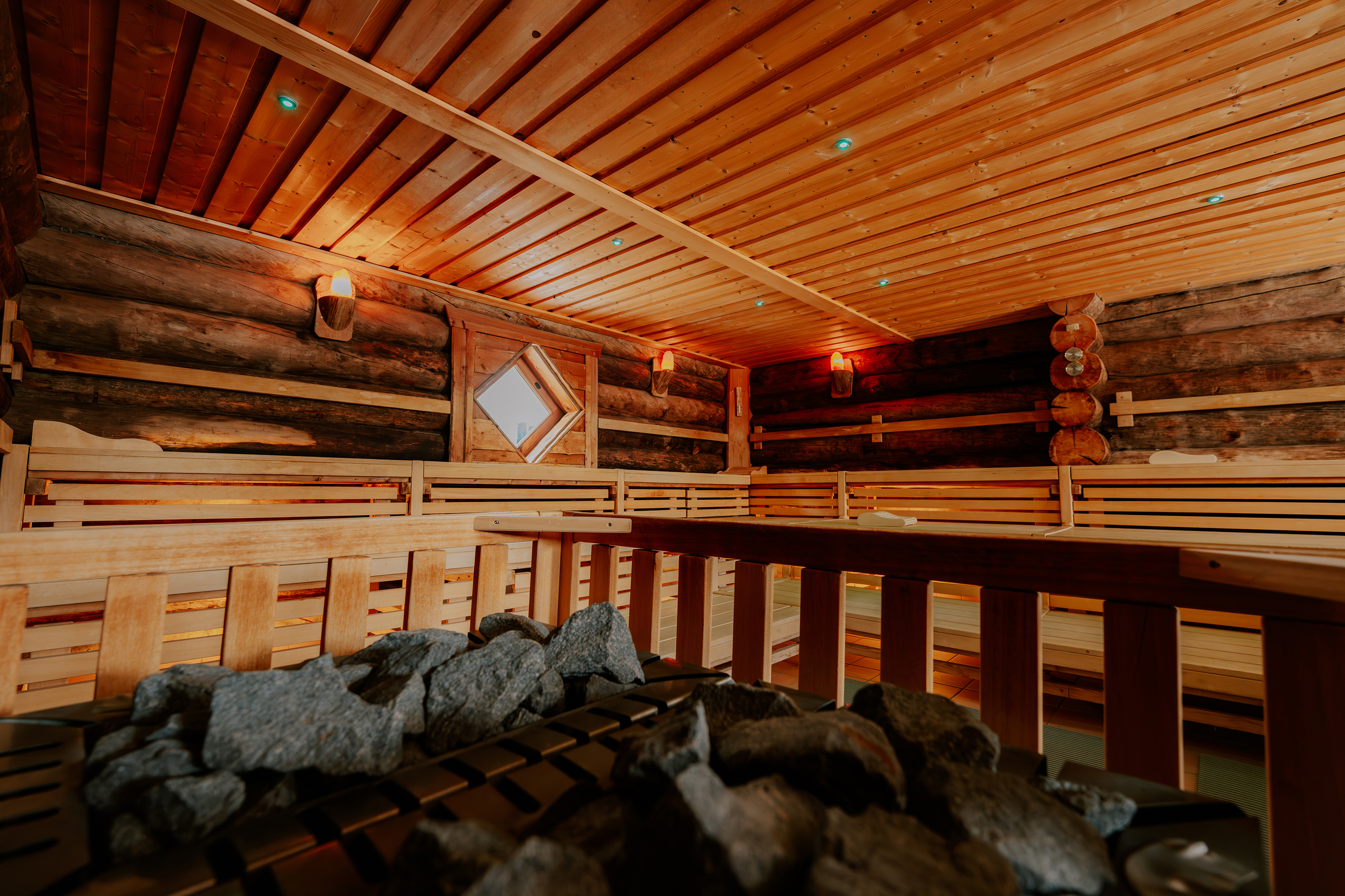 Eine leere Sauna mit Holzverkleidung und Steinen im Vordergrund.