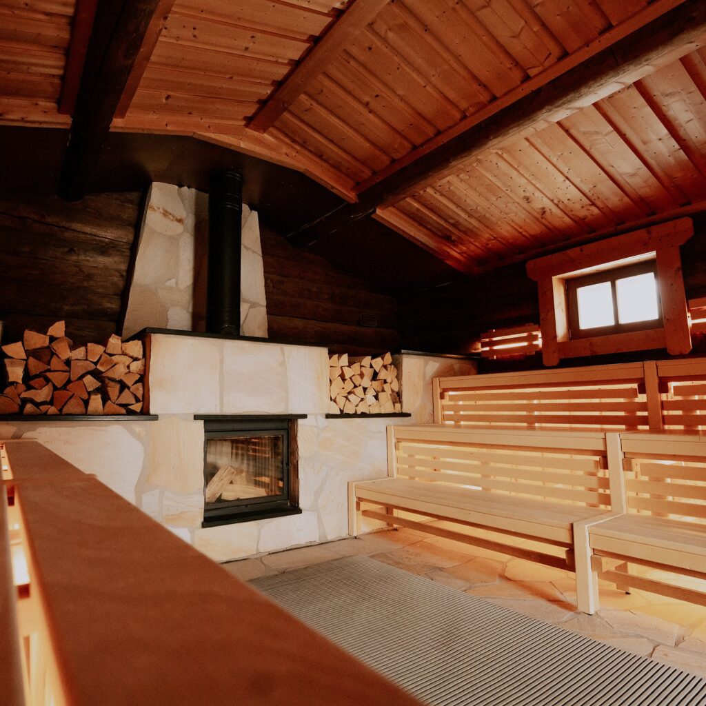 Rustikale Holzsauna mit heller Innenausstattung und gestapeltem Brennholz.